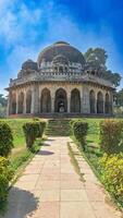 uralt Grab von Muhammad Schah sayyid im lodhi Garten im Neu Delhi. das Grab ist architektonisch Wunder mit ein kompliziert Schnitzereien auf Fassade und groß Kuppel. üppig Grün Gras und beschwingt Gelbgrün Sträucher foto