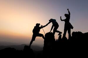 Silhouette von Person Wanderer Klettern oben Berg Cliff und einer von Sie geben Portion Hand. Menschen Erfolg, Mannschaft Arbeit Konzept. foto