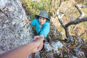 Person Frauen Wanderer Klettern oben Berg Cliff und einer von Sie geben Portion Hand. Menschen Erfolg, Mannschaft Arbeit Konzept. foto