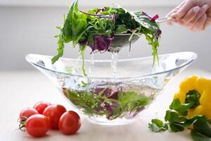 Hände Waschen Gemüse Pfeffer, Grüner Salat und Tomaten beim Zuhause Küche Super schleppend Bewegung Schuss von fliegend schneidet von bunt Gemüse und Wasser Tropfen foto