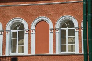 Element von das Fassade von ein rot Backstein Gebäude mit Weiß gewölbt Fenster. foto