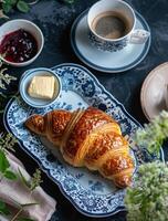 ein Croissant und Kaffee auf Blau und Weiß Teller foto