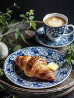 Blau und Weiß Teller mit Croissant und Tasse von Kaffee foto