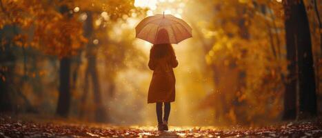 Frau Gehen durch Herbst Wald mit Regenschirm während golden Stunde foto