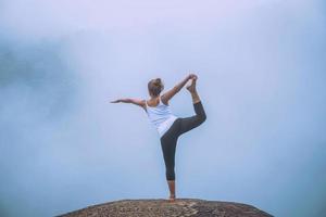 asiatische frauen entspannen sich im urlaub. spielen, wenn Yoga. auf der Bergfelsenklippe foto