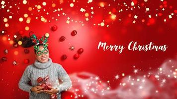 Weihnachten neues Jahr. junge Frau, gekleidet in warmen Pullover mit Requisiten Ball rot mit Weihnachtsschmuck im Urlaub auf glänzendem rotem Hintergrund. Konzept Frohe Weihnachten. foto