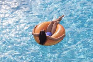 ein Frau im ein Schwimmen Schwimmbad entspannend auf ein aufblasbar Ring foto
