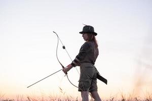 Frau mit Bogen draußen im Feld foto