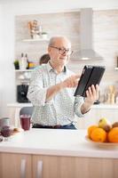 glücklicher alter Mann mit Tablet-PC foto