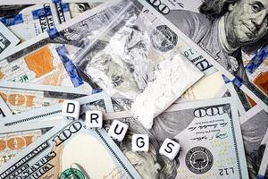 ein Tasche mit Weiß Betäubungsmittel Pulver mögen Heroin oder Kokain auf das Hintergrund von einer hundert Dollar Rechnungen. foto