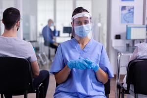 Krankenschwester mit Visier und Gesichtsmaske gegen Coronavirus, die müde in die Kamera schaut