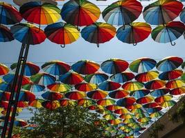 Regenschirme in verschiedenen Farben gegen den Himmel und die Sonne foto