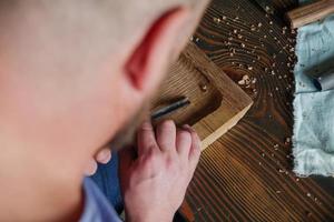 Holzschnitzer bearbeitet Holzbretter mit einem Meißel foto