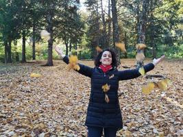 Frau wirft Blätter in die Luft foto