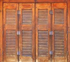 Alte orangefarbene Holzfenster mit Holzfensterläden und Metallscharnieren im griechischen Stil. foto