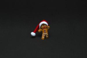 Weihnachtskonzept. Lebkuchenmann in Weihnachtsmütze auf schwarzem Hintergrund mit Kopierraum foto