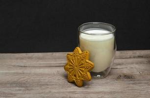 Weihnachtsmilch und Lebkuchen für den Weihnachtsmann. ein großes Glas Milch. Foto von Weihnachtsgetränk auf Holzhintergrund. Nahaufnahme