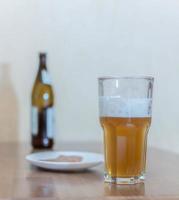 Bier in einem Glas auf einem Holztisch im Hintergrund eine Flasche foto