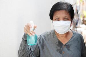 asiatisch Haushälterin tragen Weiß Maske mit Alkohol. Gesundheit und Krankheit Konzept foto