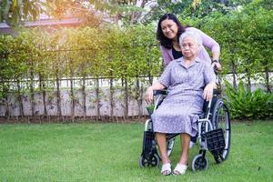 Pflegekraft Tochter hilft asiatischen Senioren oder älteren alten Damen auf Elektrorollstuhl im Park. foto