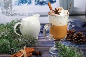 Heißer Kaffee Latte mit Zimtstangen, mit Zimt bestreut. Weihnachtsschmuck, Zweige eines Weihnachtsbaums. Urlaubskonzept neues Jahr. foto