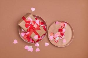 Valentinstag Zusammensetzung. Geschenkbox, Konfetti, Umschlag Postkarte mit rotem Herzen auf pastellfarbenem Hintergrund foto