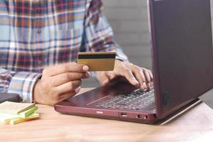 Mannhände, die Kreditkarte halten und mit Laptop online einkaufen