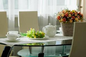 Esstisch mit Geschirr für Tee, Trauben, Blumen foto