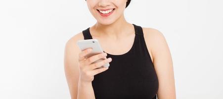 lächelnde Frau hält Handy. Closeup junge glücklich schöne asiatische Japanerin. Mädchen, das Handy lokalisiert auf weißem Hintergrund betrachtet. positiver Gesichtsausdruck menschliche Emotionen. Platz kopieren. foto
