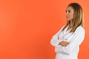 Frauen Arzt mit Gesicht Maske lächelt im Vorderseite von das Kamera.orange Studio Hintergrund foto