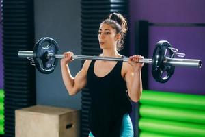 athletische Frau im Fitnessstudio, die Gewichte im Fitnessstudio hebt foto