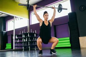 athletische Frau im Fitnessstudio, die Gewichte im Fitnessstudio hebt foto