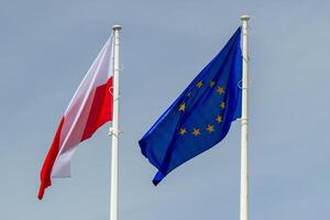 Warschau, Masowisch Woiwodschaft, Polen ,2024 - - Flaggen von das europäisch Union und Polen Nächster zu jeder andere auf Fahnenmasten gegen das Himmel. Jahrestag von Polens Beitritt zu das europäisch Union foto