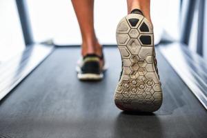 Männliche muskulöse Füße in Turnschuhen, die auf dem Laufband im Fitnessstudio laufen.