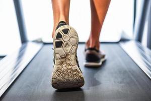Männliche muskulöse Füße in Turnschuhen, die auf dem Laufband im Fitnessstudio laufen.