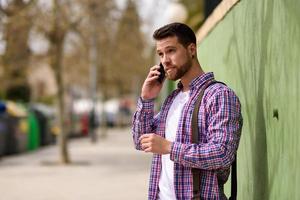 junger Mann, der mit seinem Smartphone im städtischen Hintergrund spricht. Lifestyle-Konzept. foto