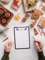 Draufsicht Hände schreiben Neujahrsziele, Auflösung oder Einkaufsliste auf einem leeren Papier. Mock-up-Design foto