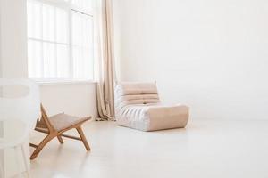 minimalistisches helles und luftiges Innendesign, weißer und beigefarbener Stuhl, Teppich und Kissen foto