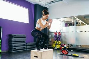 athletische Frau macht Kniebeugen auf Box im Fitnessstudio foto