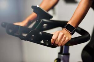 Frau in einem Fitnessstudio beim Spinning oder Cyclo Indoor mit Smartwatch foto