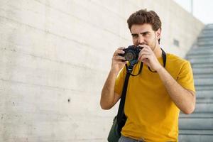 Tausendjähriger Mann, der mit einer Spiegelreflexkamera fotografiert foto