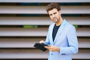 Geschäftsmann mit einem digitalen Tablet in der Nähe eines Bürogebäudes foto