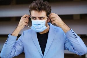 Geschäftsmann, der eine chirurgische Maske zum Schutz vor dem Coronavirus aufsetzt. foto