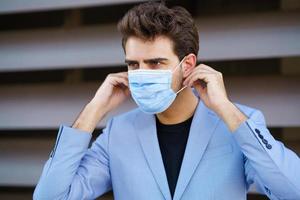 Geschäftsmann, der eine chirurgische Maske zum Schutz vor dem Coronavirus aufsetzt. foto