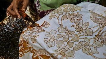 Nahaufnahme der Hand, um Batik-Tulis auf dem Stoff mit Canting zu machen foto