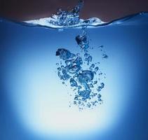blaue transparente Wasserwellenspritzenzusammenfassung mit Wasserblasen auf Blau. foto
