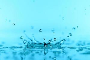 hellblaue transparente Wasserwellenoberfläche mit Spritzblase auf Blau.