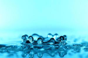 hellblaue transparente Wasserwellenoberfläche mit Spritzblase auf Blau.