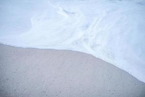 die Schaumwelle am Sandstrand. sanfte Wellen an der Küste, die sich ruhig und angenehm zum Entspannen anfühlen.