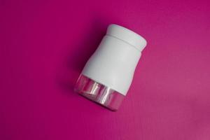 Salz- oder Pfefferstreuer schräg stellen und aus der Draufsicht aufstellen. Gewürzpulverbehälter in weiß und schwarz. Gewürzstreuer auf rosa Hintergrund. foto